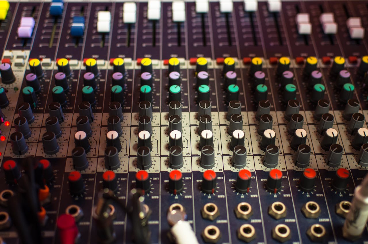 Detailed view of a professional audio mixing console with multicolored knobs in a studio setting.